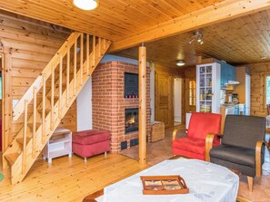 A wooden interior with a fireplace, a staircase, and a dining area.