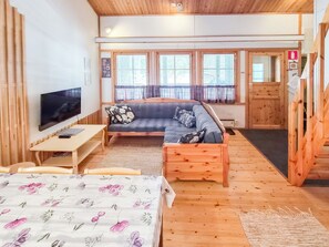 Una habitación acogedora con cama, sofá, televisión y ventana con persianas.