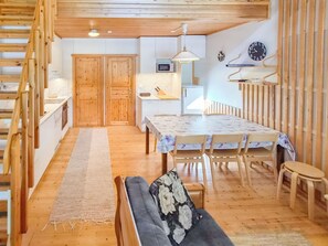 Un intérieur en bois comprenant un coin repas, un canapé et un escalier.