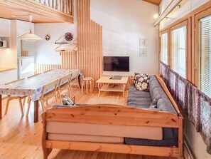 Un espace de vie chaleureux et accueillant, avec un lit en bois, une table à manger, un téléviseur et un canapé.
