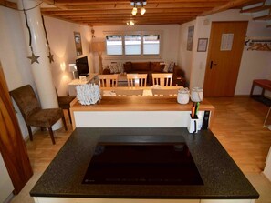 A compact kitchen with a black induction cooktop, wooden dining table, and chairs. - Bühl 13 Appartement/Fewo 8-Bettwohnung by Interhome (Engelberg)