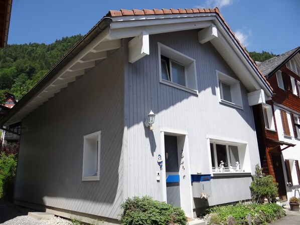 A two-story house with a grey exterior, white trim, and a brown roof.