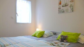A bedroom with two beds, striped bedding, green pillows, and a wall art piece.