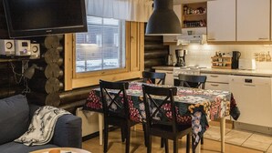 Un salon confortable avec un canapé, une table à manger et des chaises, un téléviseur et un coin cuisine équipé de placards et d’appareils électroménagers.