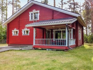 A red wooden house with a porch and two windows.