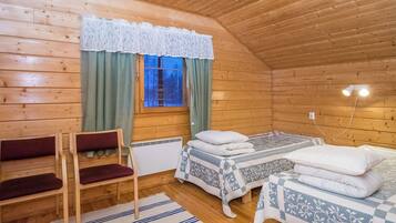 A cozy wooden cabin room with two beds, a bench, and a window with curtains.