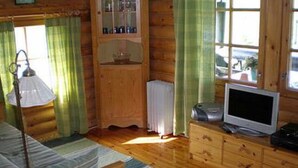 Een houten hut met een bed, een televisie en een kast.