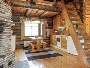 A rustic kitchen with a wooden table, bench, and a wooden staircase. - Kulpakko 3 by Interhome (Rovaniemi)