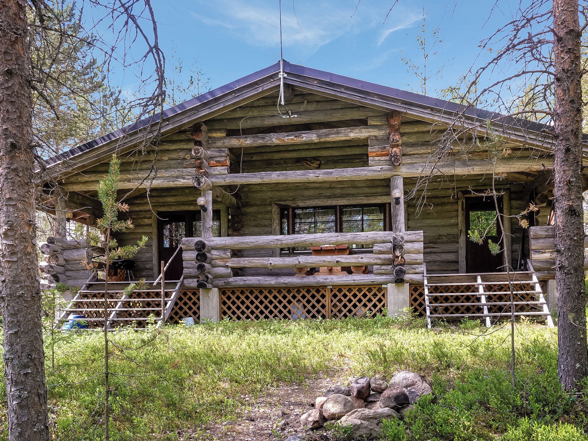 A log cabin with a porch, a front door, and a staircase leading up to the entrance.