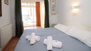 A hotel room with a bed, towels, a radiator, a window with curtains, and a wall-mounted light. - El Junco by Interhome (Benidorm)