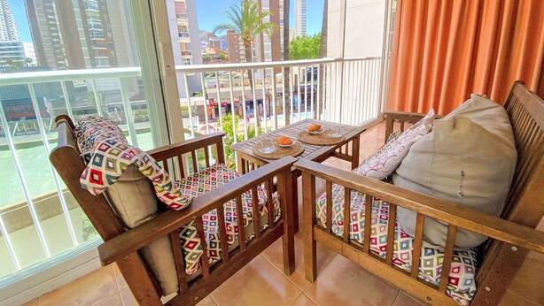 A balcony with a wooden bench and table, featuring a city view. - El Junco by Interhome (Benidorm)