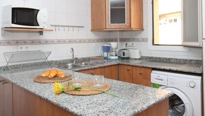 A kitchen with granite countertops, a microwave, a coffee maker, and a washing machine. - El Junco by Interhome (Benidorm)