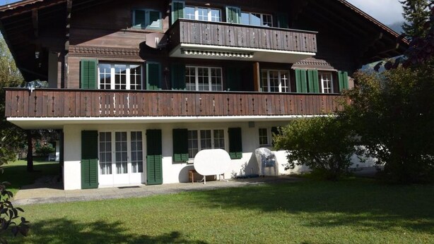 A two-story wooden house with green shutters and a balcony. - Elena # 1 by Interhome (Lenk)