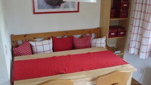 A bedroom with a wooden bed, red bedding, and two wooden chairs. - Elena # 1 by Interhome (Lenk)
