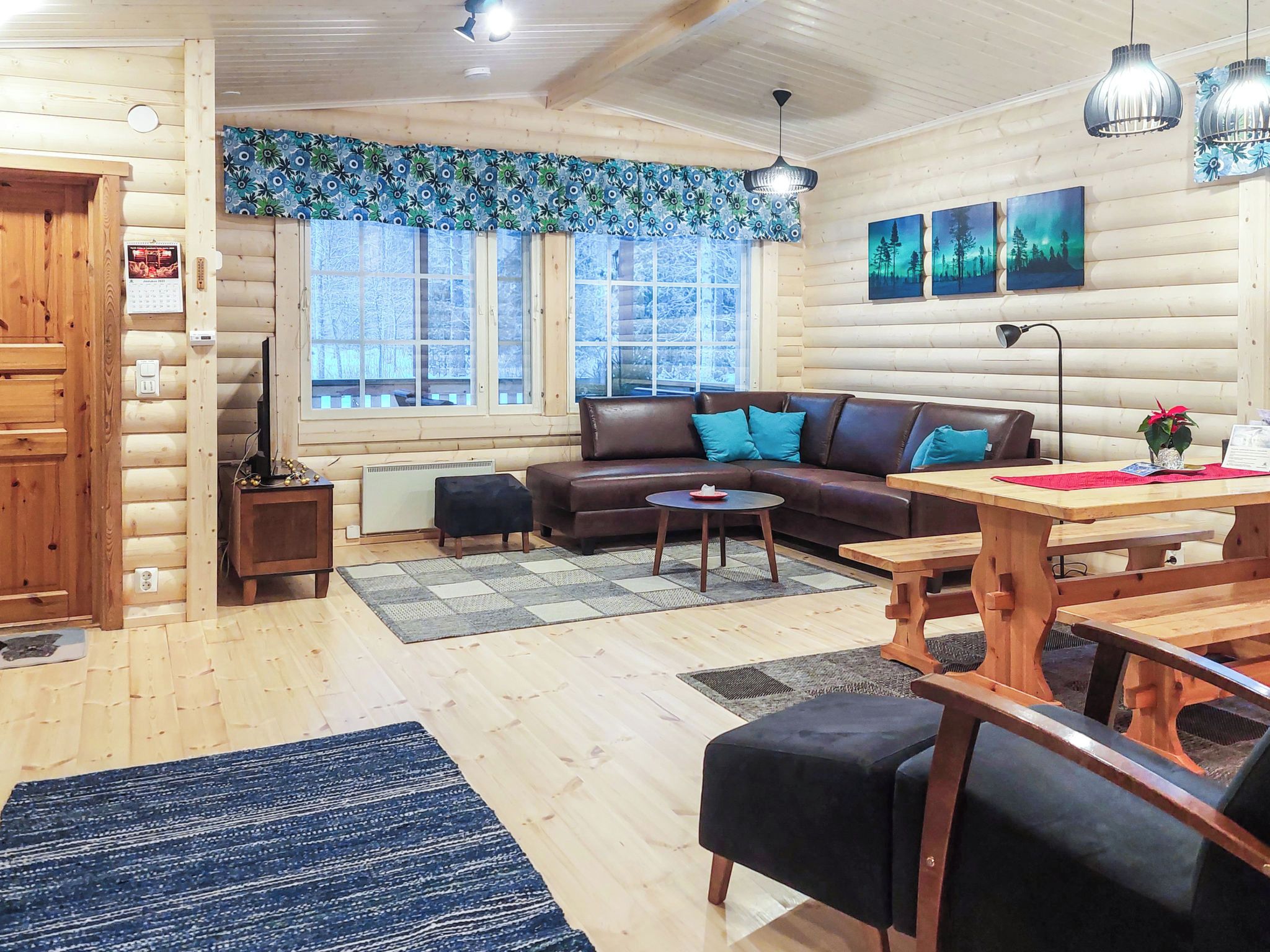 Een vakantiehuisje van binnen, met een bank, salontafel, eettafel en een open haard.