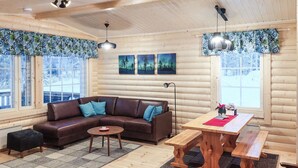 A cozy cabin interior with a brown leather sofa, a wooden dining table, and a bench. - Lassinmaja by Interhome (Hartola)