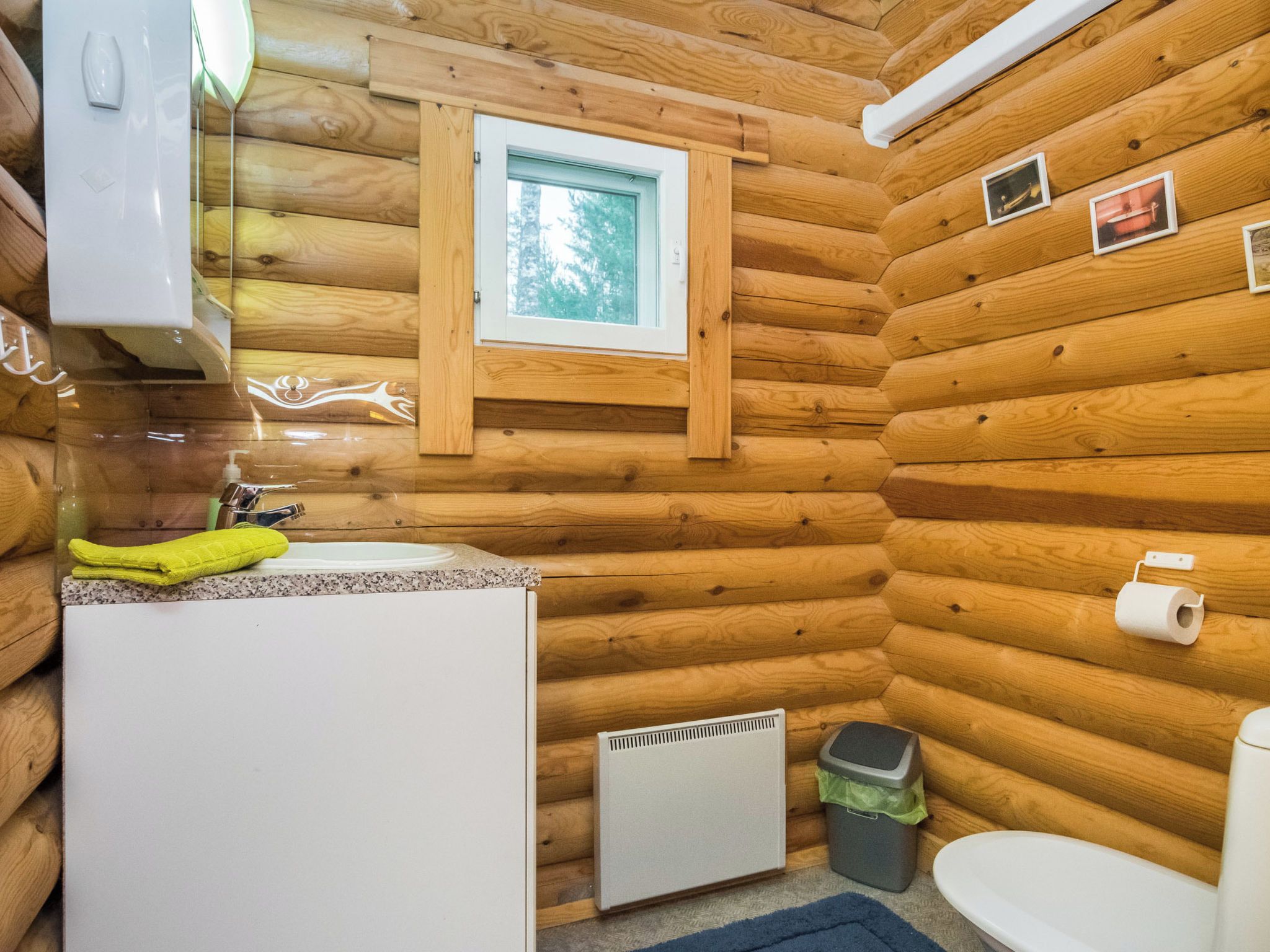 Pieni, puinen mökkityylinen kylpyhuone, jossa on pesuallas, wc ja ikkuna.
