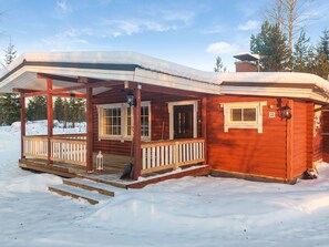 A wooden cabin with a covered porch and a small deck, surrounded by snow. - Lassinmaja by Interhome (Hartola)