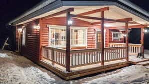 A log cabin with a wooden porch and a covered entryway. - Lassinmaja by Interhome (Hartola)