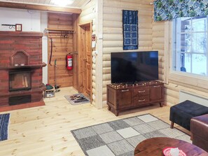 A log cabin interior with a fireplace, television, and a window with a view. - Lassinmaja by Interhome (Hartola)
