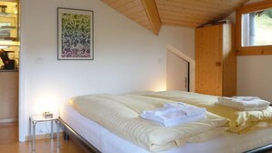 Ein Schlafzimmer mit einem Bett, Holzboden, einem Fenster und einem Gemälde an der Wand.