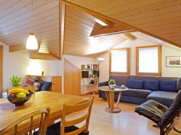 Ein gemütliches Wohnzimmer mit Holzboden, einem Esstisch, Stühlen, einer Couch und einem kleinen Beistelltisch.