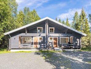 Eine zweistöckige Holzhütte mit Satteldach, Holzverkleidung und einer Veranda.