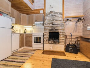 A kitchen with wooden cabinets, a stone fireplace, and a hanging rack.