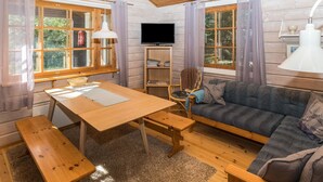 Een gezellig houten interieur met een eettafel, bankjes, een bank en een televisie.