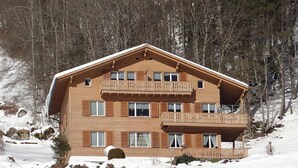 Un immeuble en bois à plusieurs étages, doté de balcons, entouré de neige et d’arbres.