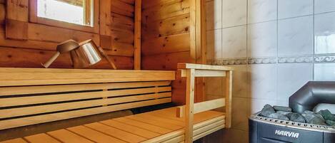 A wooden sauna with benches, a small table, and a Harvia sauna heater.