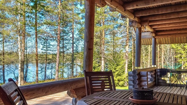 A wooden deck with a table and chairs, overlooking a lake surrounded by trees. - Honkala by Interhome (Soini)