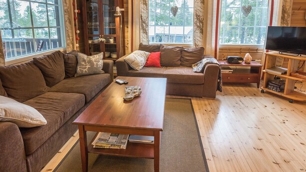 A cozy living room with a brown sofa, a wooden coffee table, and a television on a wooden stand. - Kirikuru 2 by Interhome (Äkäslompolo)