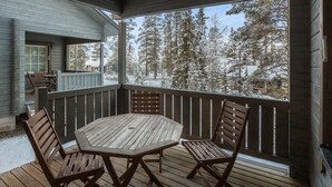A wooden deck with a round table and four chairs, overlooking a snowy landscape with trees. - Kirikuru 2 by Interhome (Äkäslompolo)