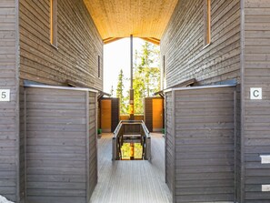 Un couloir aux murs en bois et un escalier central menant à une fenêtre.