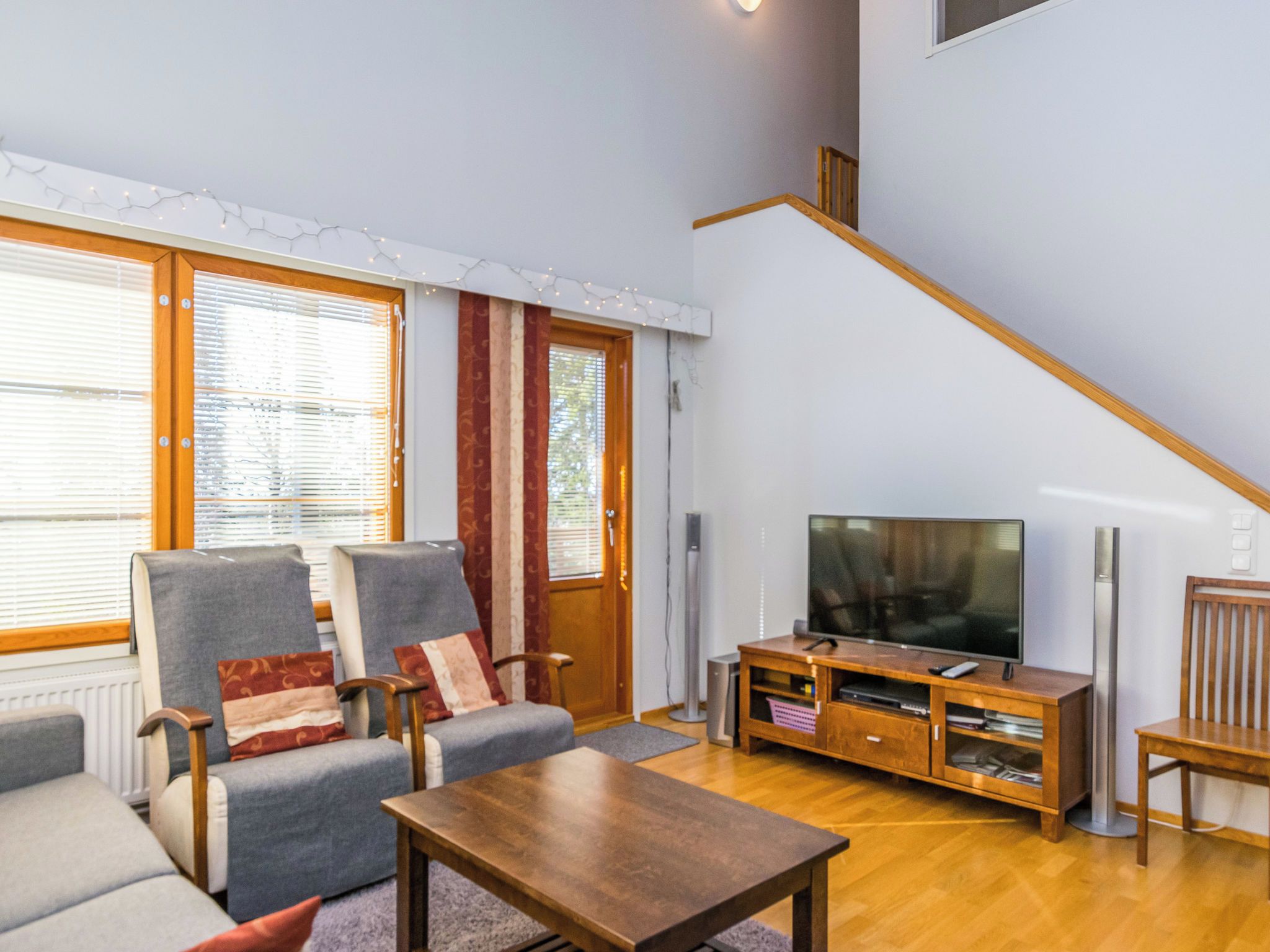 Un salon comprenant un canapé, des fauteuils, une table basse, un téléviseur et un escalier.