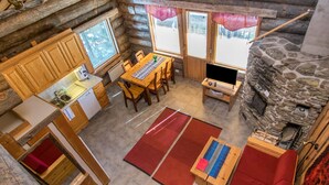 A log cabin interior with a kitchen, dining area, and stone fireplace. - Rinnekieppi 1 by Interhome (Kuusamo)