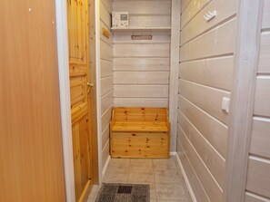 A small, narrow room with wooden walls, a wooden bench, and a tiled floor.
