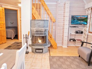 Uma sala de estar aconchegante com lareira de pedra, escada de madeira e televisão na parede.
