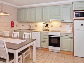 Cozinha com armários verde-claros, cafeteira, micro-ondas e lava-louças.
