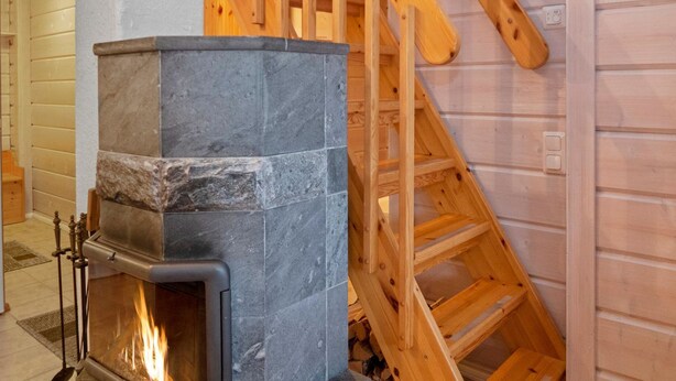 Ein Kamin aus Stein mit einer Holztreppe, die zu einer oberen Ebene führt.