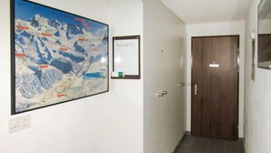En hall med en dörr av trä, en inramad välkomstskylt och en stor karta på väggen.
