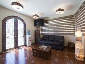 A living room with a sofa, coffee table, water dispenser, and a TV.