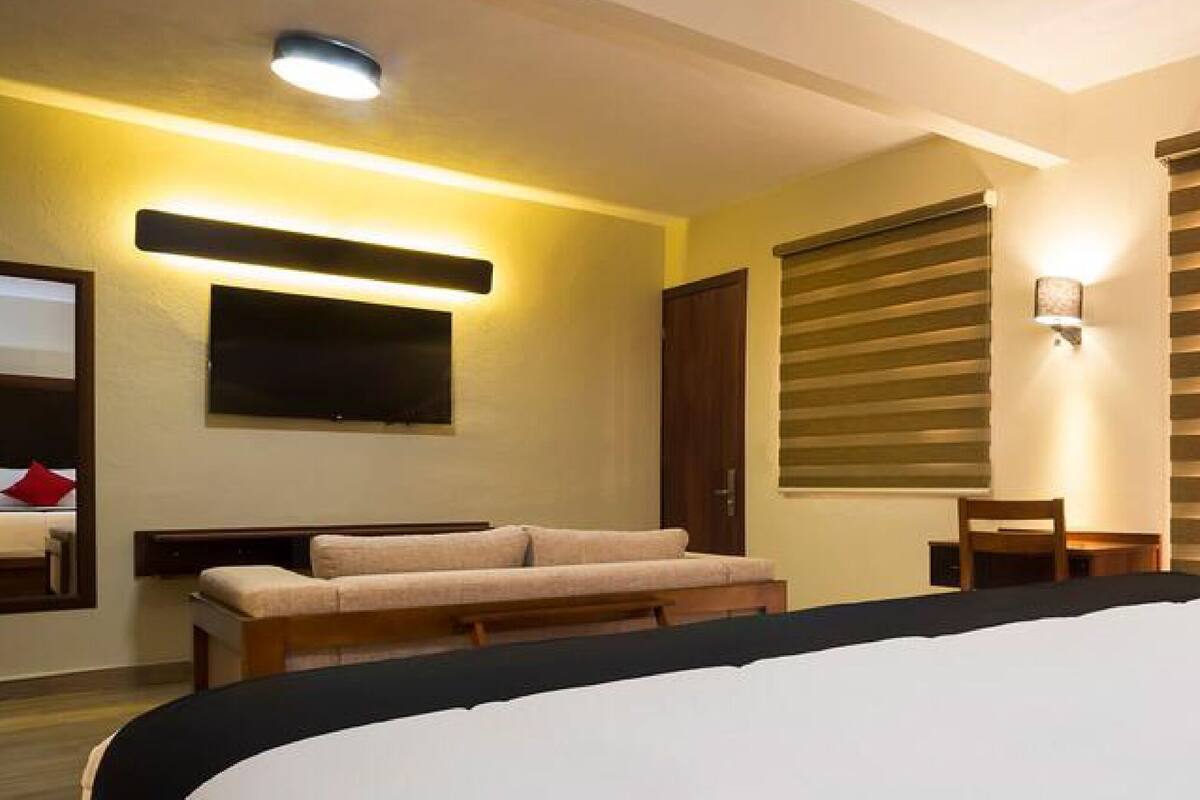 Une chambre d’hôtel équipée d’un lit, d’un canapé, d’un bureau et d’un téléviseur fixé au mur.