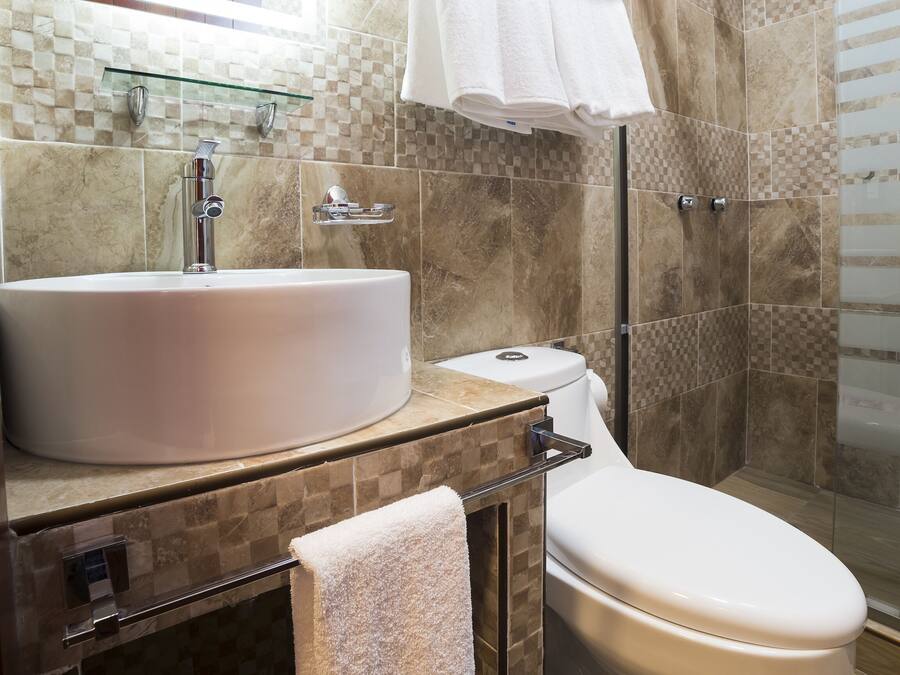Un baño moderno con un lavamanos grande, inodoro y cabina de ducha de vidrio.