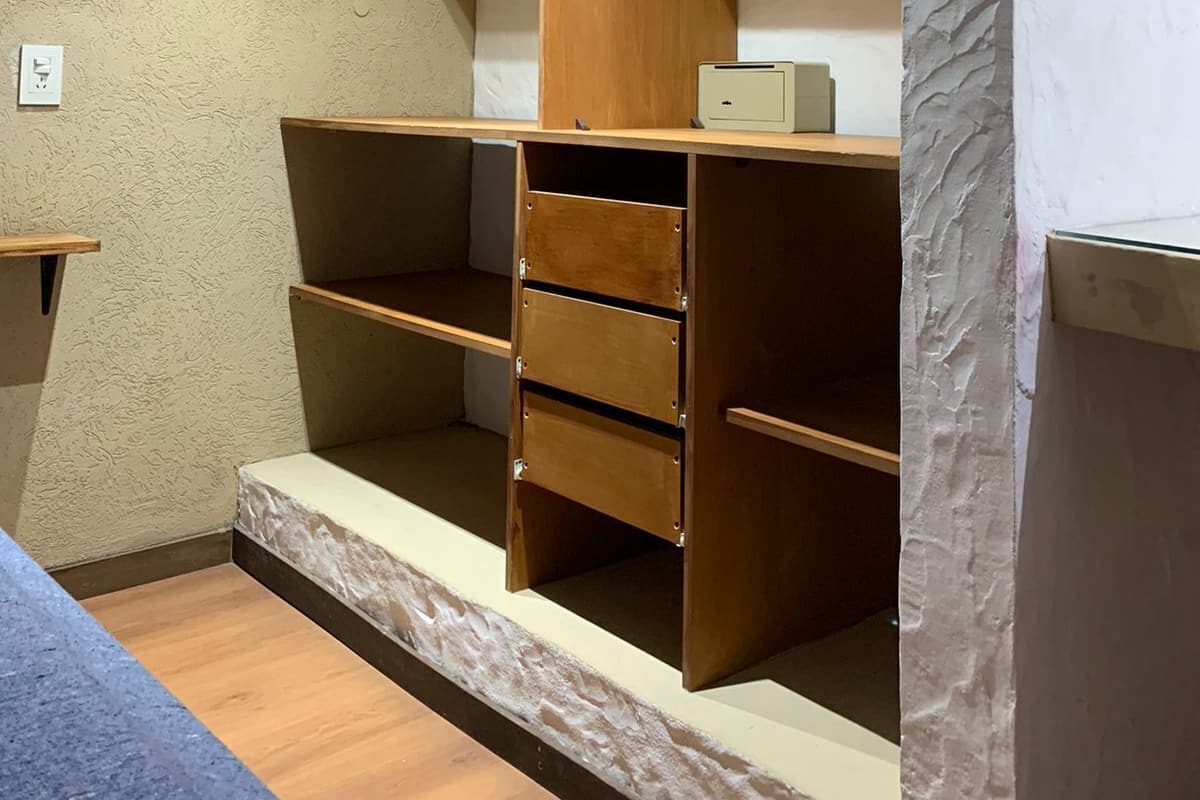 Une pièce dotée d’une armoire en bois intégrée, d’un petit bureau et d’un banc.