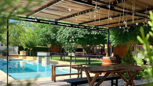 A covered outdoor area with a pool, wooden benches, and tables. - La Divina Pereza (San Rafael)