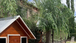 A wooden cabin with a porch, a play area with pink tables, and a swing set. - La Divina Pereza (San Rafael)