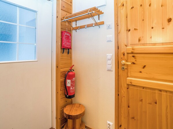 A wooden door with a small stool and a fire extinguisher mounted on the wall.