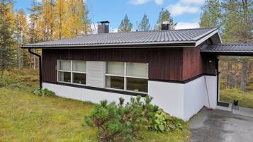 Moderni talo, jossa on kalteva katto, suuret ikkunat ja puinen julkisivu.